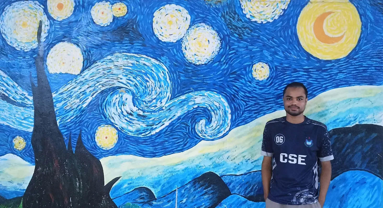 Monirul Hasan Mithu in front of a large painted mural